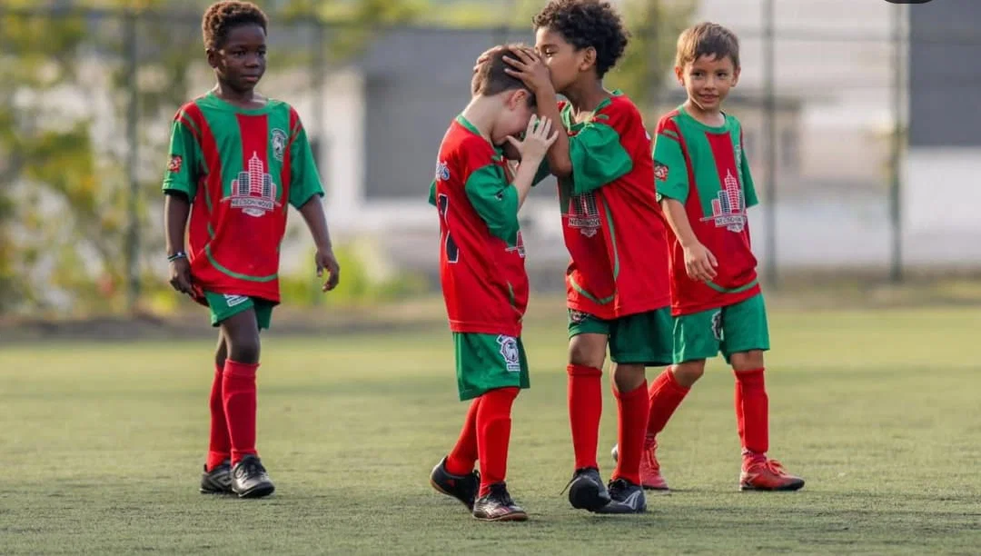 Alunos da CS Marítimo Vale Europeu com uniforme verde e vermelho durante treino no campo